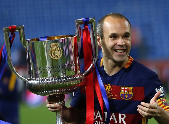 Barcelona&#039;s Andres Iniesta carries the trophy after winning the final of the Copa del Rey soccer match between FC Barcelona and Sevilla FC at the Vicente Calderon stadium in Madrid, Sunday, May 2 ...