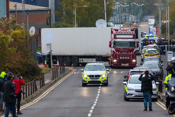 epa07943547 Police drive the lorry container along the road from the scene in Waterglade Industrial Park in Grays, Essex, Britain, 23 October 2019. A total of 39 bodies were discovered inside a lorry  ...