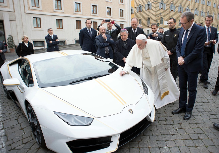 Pope Francis writes on the bonnet of a Lamborghini donated to him by the luxury sports car maker, at the Vatican, Wednesday, Nov. 15, 2017. The car will be auctioned off by Sotheby&#039;s, with the pr ...