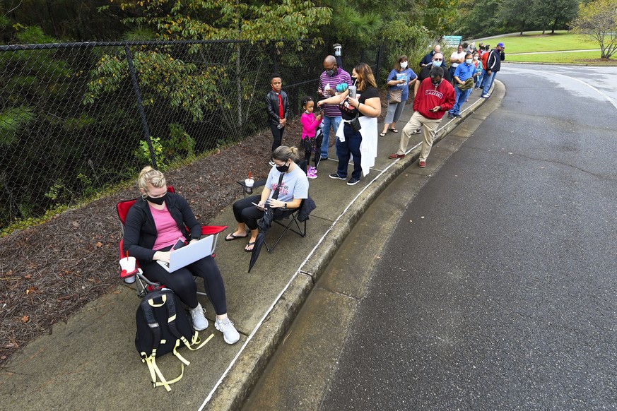epa08738732 University of Georgia student Courtney Wetzel (L) participates in a Zoom online class as she and her friend Ashley Lee (2L) wait with others in a line to vote that has an estimated 3-hour  ...