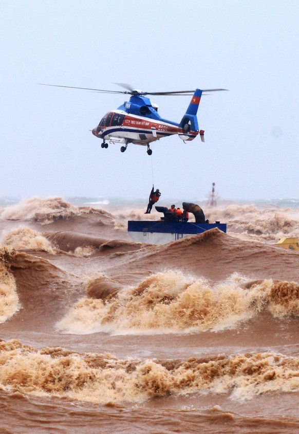 epa08735555 A helicopter from Ministry of Defence rescue stranded crew members at the sea, in Quang Tri province, Vietnam, 11 October 2020. Heavy rains and floods killed nine people and left 11 missin ...