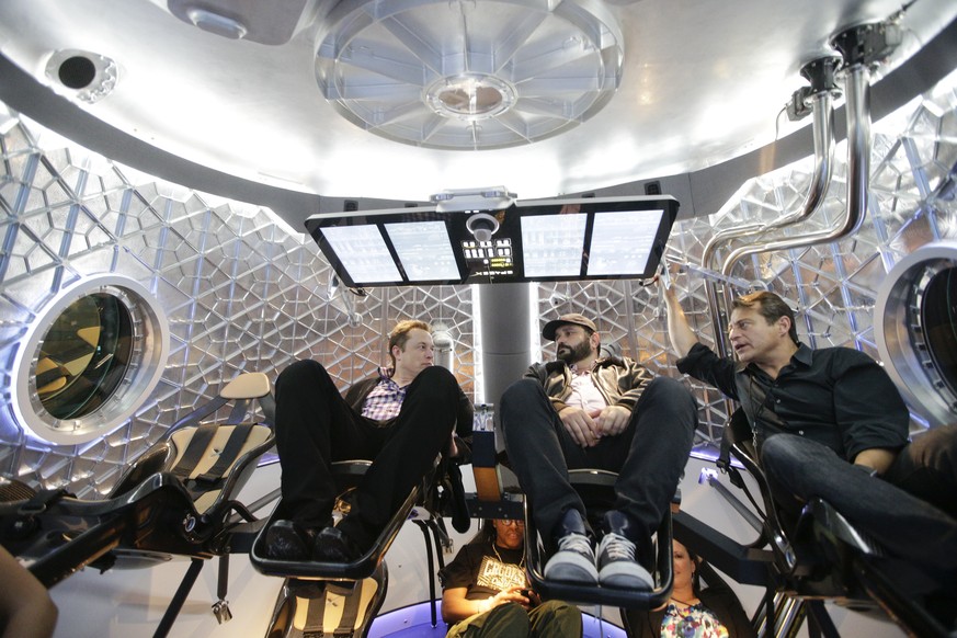FILE - In this Thursday, May 29, 2014 file photo, Elon Musk, left, CEO and CTO of SpaceX, talks with invited guests inside a mockup of the SpaceX Dragon V2 spacecraft at the headquarters in Hawthorne, ...
