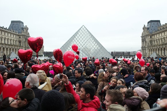 Couples share a kiss during a kissing flashmob in celebration of Valentine&#039;s Day, in front of the Pyramid at the Louvre Museum, in Paris, Friday, Feb. 14, 2014. Valentine&#039;s Day is observed o ...