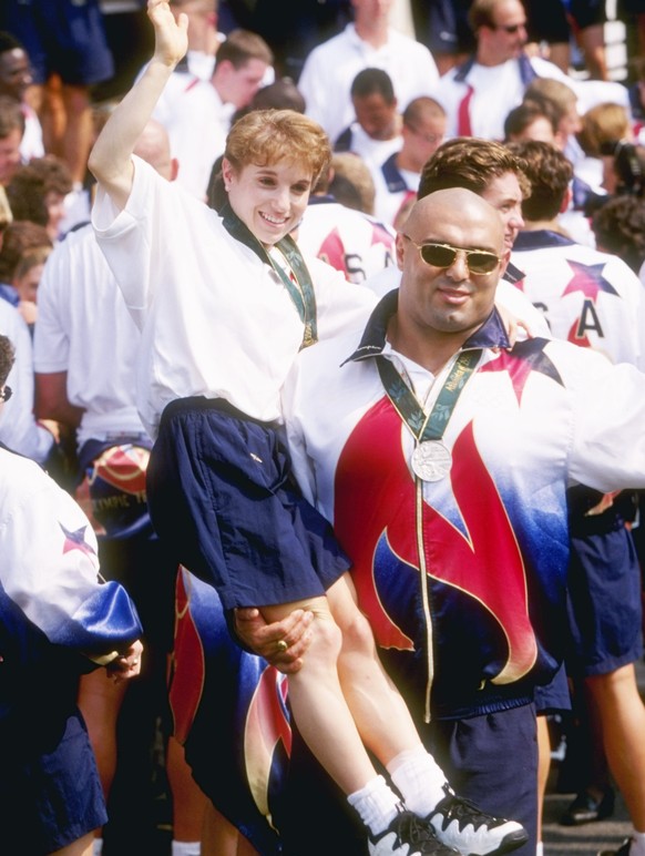 14 Aug 1996: Gymnast Kerri Strug, left, is held up by wrestler Matt Ghaffari of the USA during a ceremony with President Bill Clinton for all U.S. Olympic medalists at the 1996 Centennial Olympic Game ...