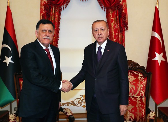epa08074038 A handout photo made available by Turkish President Press Office shows Turkish President Recep Tayyip Erdogan (R) shaking hands with Chairman of the Presidential Council of Libya Fayez al- ...