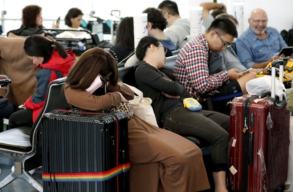 Passengers rest as their flights were cancelled because of Typhoon Hagibis, at Haneda Airport in Tokyo, Saturday, Oct. 12, 2019. Tokyo and surrounding areas braced for a powerful typhoon forecast as t ...