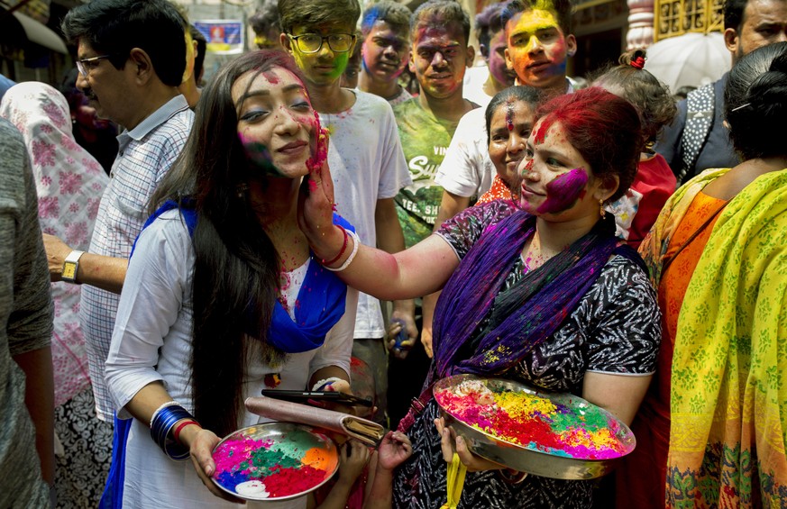 epa07452311 Bangladeshi Hindu women smear colored powder on each other during the Holi Festival in Dhaka, Bangladesh, 21 March 2019. Holi is celebrated on the full moon day in the Hindu month of Phalg ...