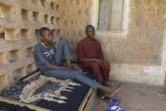 Usama Aminu, 17, a kidnapped student of Government Science Secondary School who escaped from bandits, left, and his father Aminu Male, sit together during an interview with Associated Press in Kankara ...