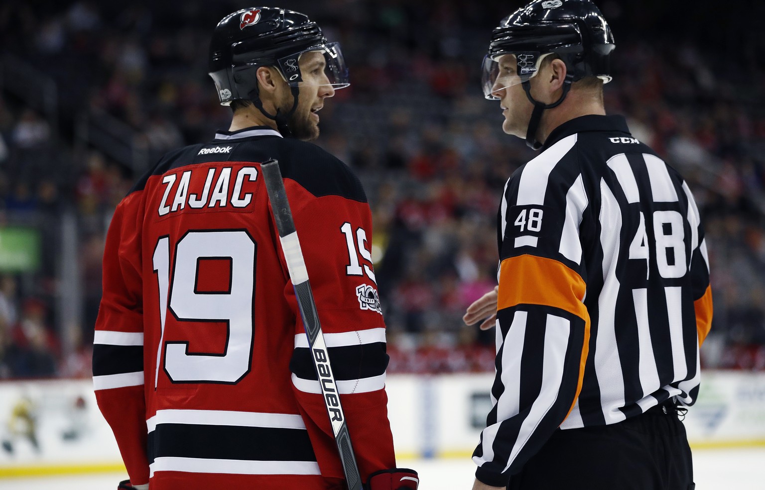 CORRECTS ID TO CHRIS SCHLENKER NOT GARRETT RANK FILE - This March 28, 2017, file photo shows New Jersey Devils center Travis Zajac, left, talking to referee Chris Schlenker during the first period of  ...