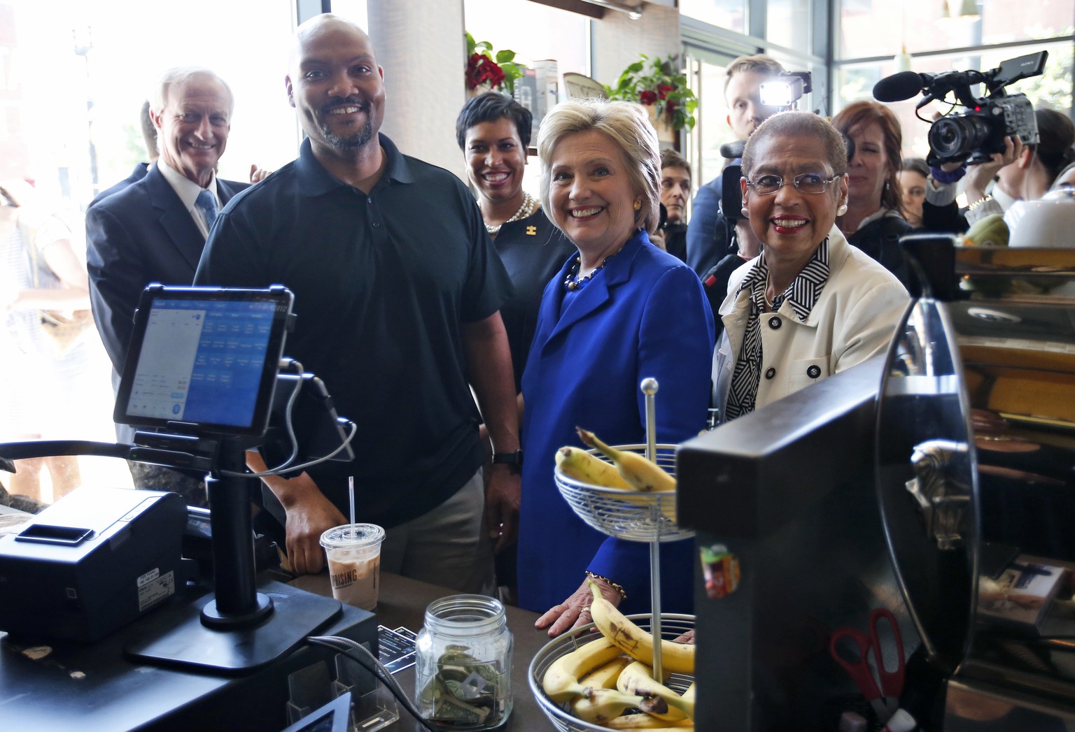 Democratic presidential candidate Hillary Clinton, joined by, from left, Washington City Council member Jack Evans, Uprising Muffin Company owner Donnie Simpson, Washington Mayor Muriel Bowser and Del ...