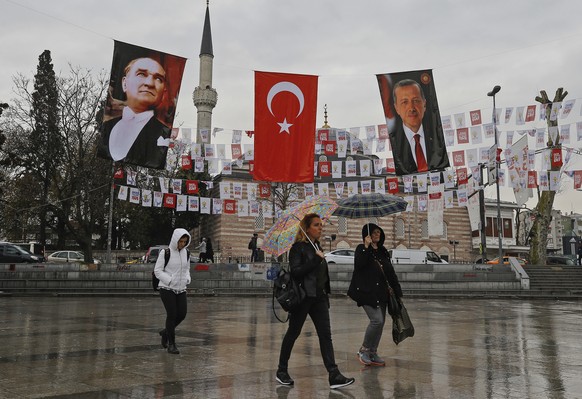 Backdropped by posters of modern Turkey&#039;s founder Mustafa Kemal Ataturk, left, and Turkey&#039;s President Recep Tayyip Erdogan, right, people walk in Istanbul, Friday, April 7, 2017. Turkey is h ...