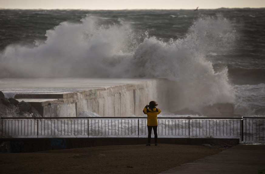 A woman photographs the Mediterranean sea during strong winds in Barcelona, Spain, Monday, Jan. 20, 2020. Two people have died as storms carrying heavy snowfalls and gale-force winds lashed many parts ...