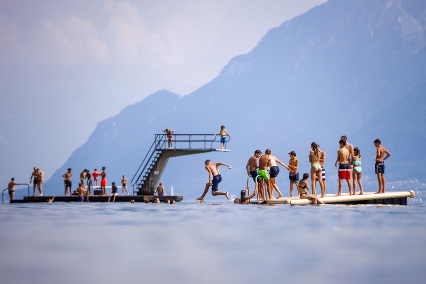 epaselect epa06909933 People enjoy the sunny and warm summer weather on a diving platform on the shore of Lake Geneva, in Lutry, Switzerland, 25 July 2018. Temperatures of up to 35 degrees Celsius cur ...