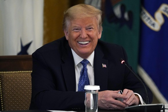 President Donald Trump smiles as he holds a debit card handed to him by Treasury Secretary Steven Mnuchin that will be used to send payments by the Treasury Department during a Cabinet Meeting in the  ...