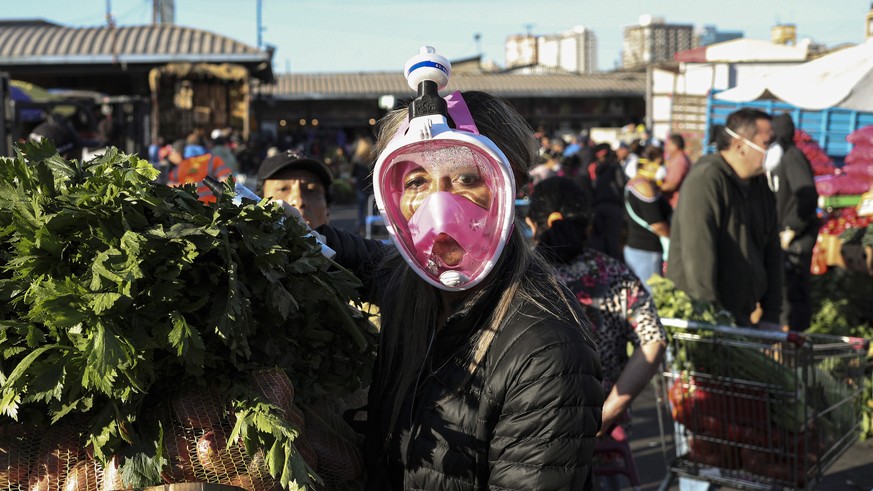 A shopper uses a snorkel mask as a precaution against the spread of the new coronavirus a she shops at La Vega market in Santiago, Chile, Thursday, April 2, 2020. (AP Photo/Esteban Felix)