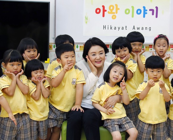 epa07433002 South Korean first lady Kim Jung-sook (C) poses for a photo with a group of South Korean kids at a South Korean school in the town of Cyberjaya in the central Malaysian state of Selangor,  ...