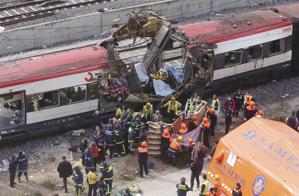 FILE - In this March 11, 2004 file photo, rescue workers cover up bodies alongside a bomb-damaged passenger train, following a number of explosions in Madrid, Spain, killing 191 people and wounding mo ...