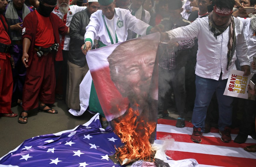 Protesters burn a poster of U.S. President Donald Trump during a rally outside the U.S. Embassy in Jakarta, Indonesia, Monday, Dec. 11, 2017. Hundreds of people staged the protest in the Indonesian ca ...