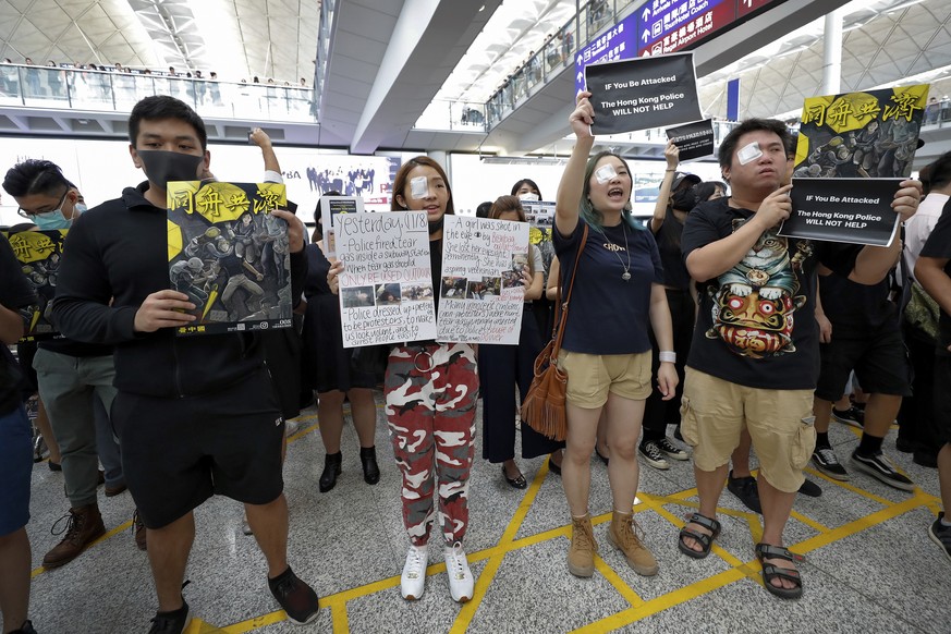 Protesters wear eyepatch during a protest at the arrival hall of the Hong Kong International Airport in Hong Kong, Monday, Aug. 12, 2019. It is reported that police shot a woman in the eye with a proj ...