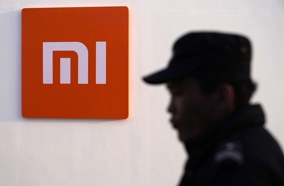 epa07382403 A security guard stands beside a logo of Xiaomi during the Xiaomi product launch ceremony in Beijing, China, 20 February 2019. Xiaomi releases its new mobile phone products &#039;Mi 9&#039 ...
