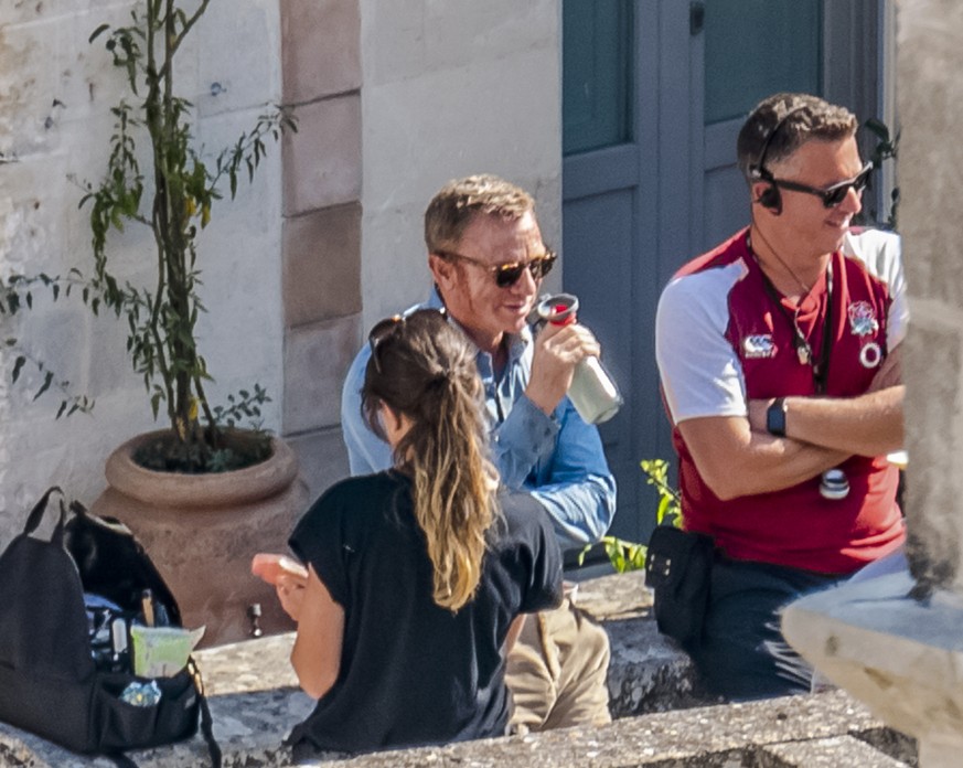 In this Sept. 12, 2019 photo, actor Daniel Craig, center, sips a drink during a break on the set of the latest James Bond movie &#039;No time to die&#039; in Matera, southern Italy. The film is due ou ...