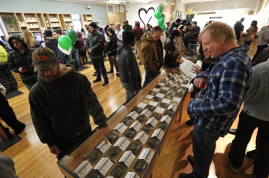 epa06412910 Customers check out cannabis samples on display while waiting in line at the Harborside cannabis dispensary in Oakland, California, USA, 01 January 2018. In November 2016, California voter ...