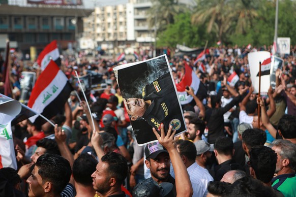 Protestors wave national flags and hold posters of Lt. Gen. Abdul-Wahab al-Saadi during a protest in Tahrir Square, in central Baghdad, Iraq, Tuesday, Oct. 1, 2019. Iraqi security forces fired tear ga ...