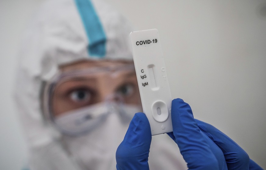 A member of the medical staff performs a rapid IgG/IgM test for COVID-19 antibody detection at a corona test center in Berlin, Germany, Wednesday, Oct. 14, 2020. (Michael Kappeler/dpa via AP)