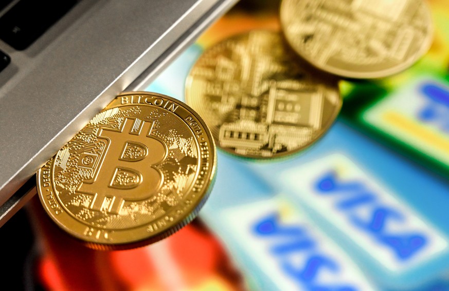 epa09018335 A bitcoin in a slot-in drive reflects in front of a monitor showing credit cards, in Duesseldorf, Germany, 17 February 2021. For the first time, the cryptocurrency Bitcoin has exceeded the ...