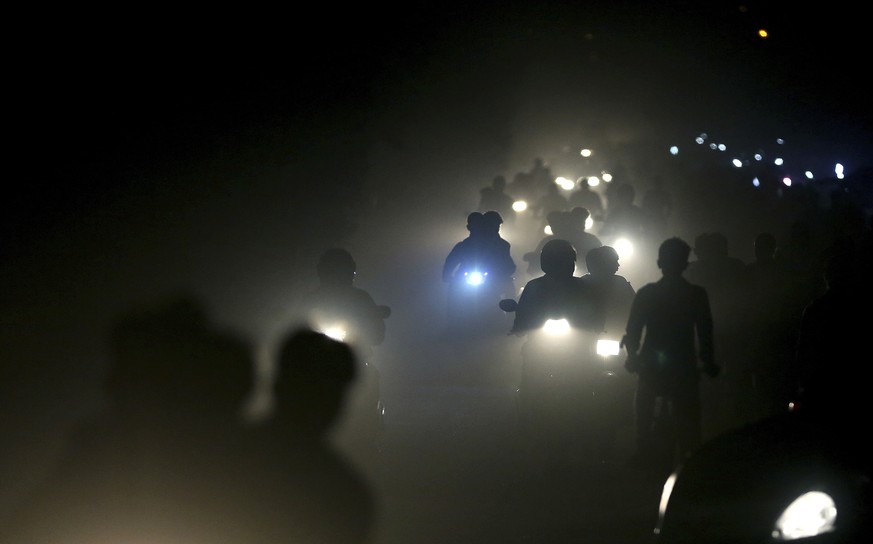 FILE - In this Friday, Nov. 10, 2017 file photo, motorists ride through a thick blanket of smog and dust on the outskirts of New Delhi, India., with microscopic particles spiking at times to 75 times  ...