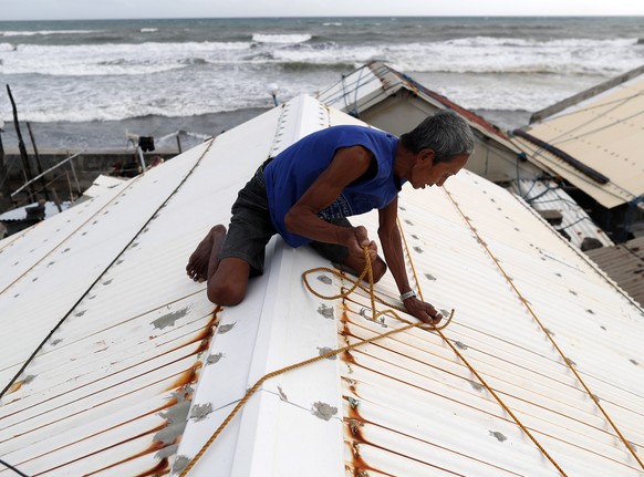 epaselect epa07018664 A Filipino villager secures the roof of a house in the town of Aparri, Cagayan province, Philippines, 14 September 2018. Typhoon Mangkhut, ranked as the most powerful of the year ...