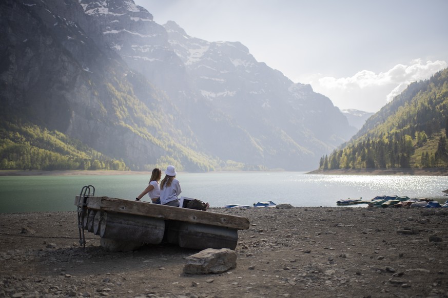 epaselect epa08380296 Two women enjoy the view over the Kloental lake with a low water level in Glarus, Switzerland, 23 April 2020. EPA/GIAN EHRENZELLER