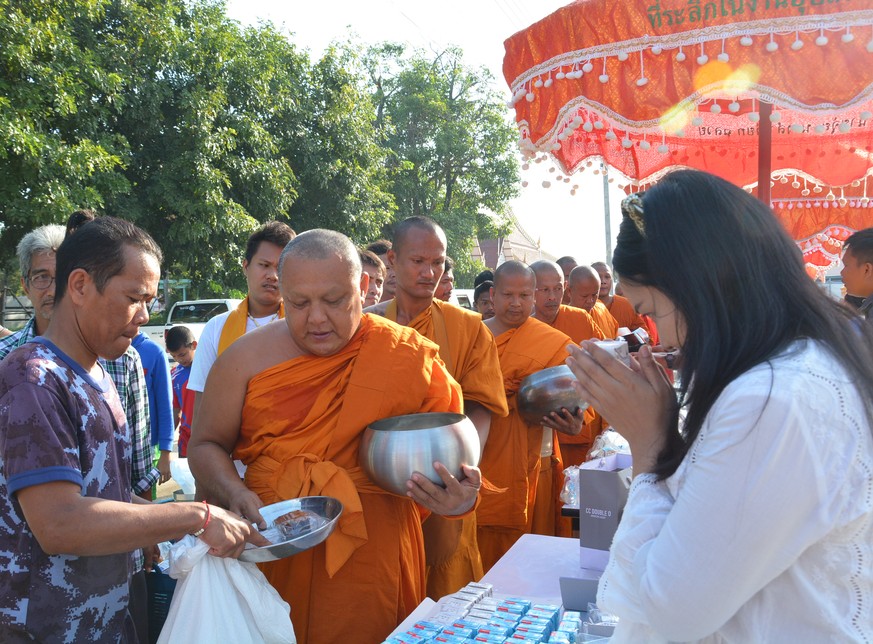Gläubige übergeben den Thai-Mönchen gekochte Speisen und Süssigkeiten.