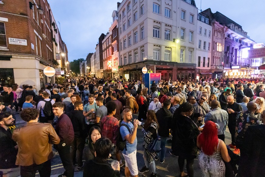 epa08528405 Revellers drink and socialize in the street during the evening in Soho, London, Britain, 04 July 2020 (issued 05 July 2020). Pubs, restaurants, places of worship, hairdressers and other bu ...