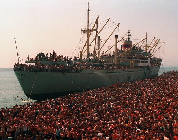 Originalbildlegende von Associated Press: «Thousands of Albanian refugees, fleeing starvation in their impoverished homeland and seeking asylum in Italy, crowd the dock in Bari, Italy, August 9, 1991  ...