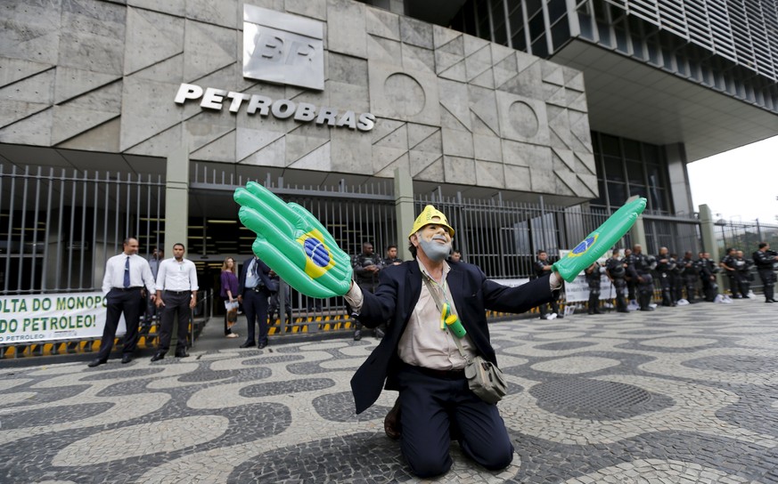 A laid-off outsourced worker, who was contracted to work for Petrobras, wears a mask of former Brazilian president Luiz Inacio Lula da Silva during a protest against recent layoffs, in front of the Pe ...