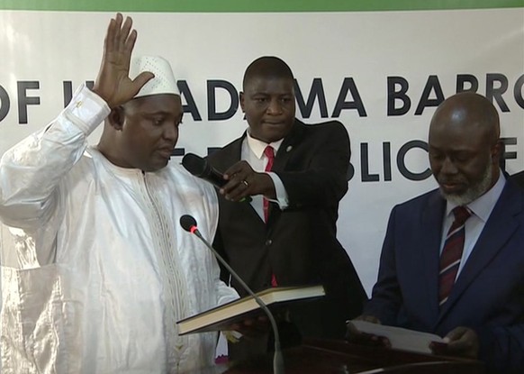 Adama Barrow, left, is sworn in as President of Gambia at Gambia&#039;s embassy in Dakar Senegal in this image taken from TV Thursday, Jan 19, 2017. A new Gambian president has been sworn into office  ...