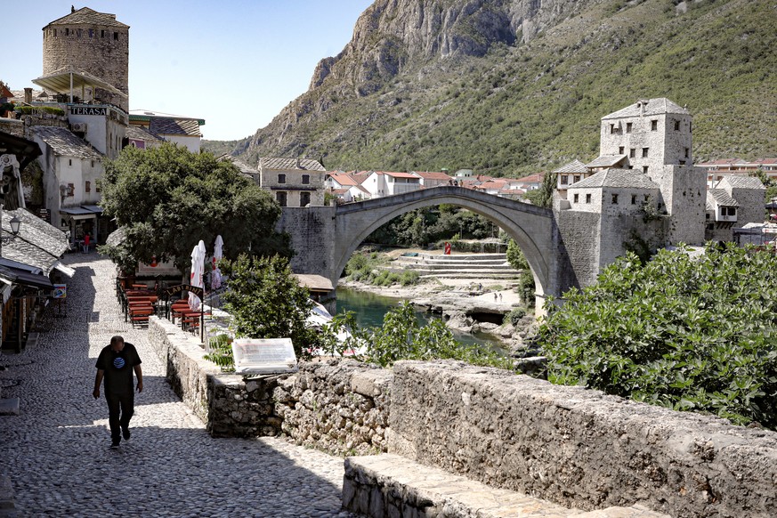 A man walks on a deserted street backdropped by the Old Bridge in Mostar, one of Bosnia&#039;s best known landmarks, Thursday, July 2, 2020. Hundreds of Bosnian tourism industry workers joined a prote ...