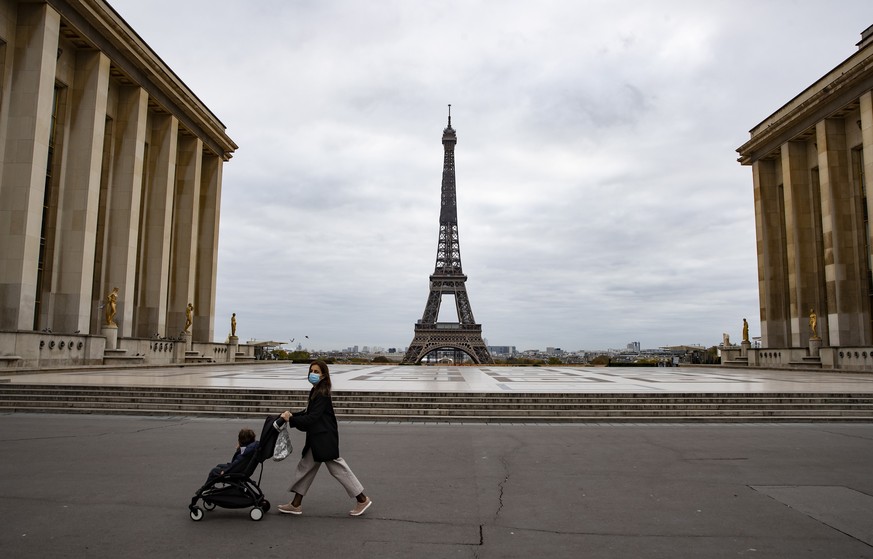 epa08786023 A woman pushes a stroller across a deserted Trocadero square near the Eiffel Tower on the first morning of the second national lockdown, dubbed reconfinement , in Paris, France, 30 October ...