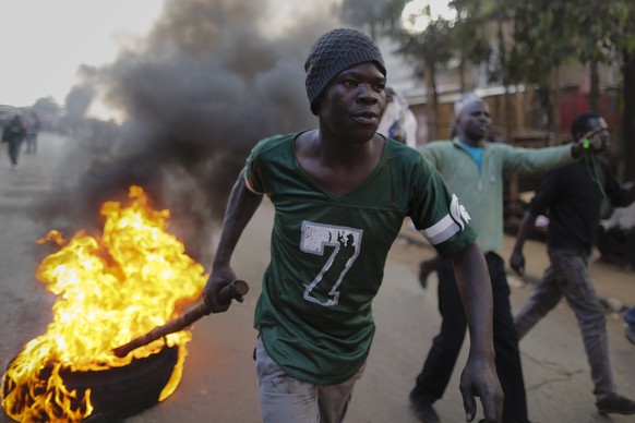 epa06134334 A supporter of the opposition leader Raila Odinga drags a burning tire down the street during a protest after Odinga announced that he rejects the provisional result of the presidential el ...