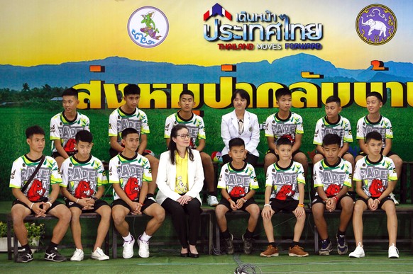 epa06896386 The 12 rescued members of the Wild Boar soccer team, with their assistant coach Ekapol Chantawong (front, L), make their first public appearance with child psychologists during a military  ...