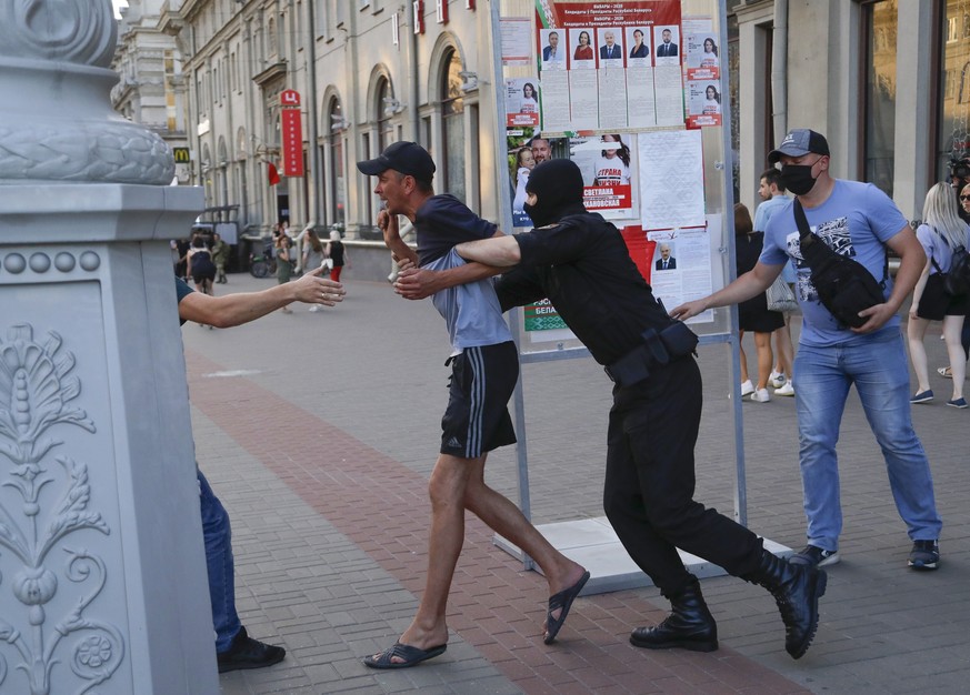 Belarusian police officers detain a man in Minsk, Belarus, Saturday, Aug. 8, 2020. On Saturday evening, police arrested at least 10 people as hundreds of opposition supporters drove through the center ...