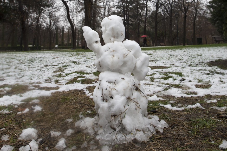 A person walks with an umbrella behind a small snowman in a park in Madrid, Spain, Monday, Feb. 5, 2018. Light snow fell on the capital Monday with more snow and cold weather expected. (AP Photo/Paul  ...
