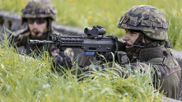 A parascout recruit in a trench holds a SG 550 assault rifle in his hands, pictured on June 17, 2013, in the recruit school for parascouts of the Swiss army in Altmatt, canton of Schwyz, Switzerland.  ...