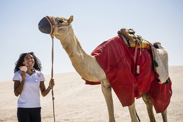 Mujinga Kambundji from Switzerland poses with a camel and the bronze medal of the women&#039;s 200 meters race during the IAAF World Athletics Championships, in the sand dunes near Doha, Qatar, Sunday ...