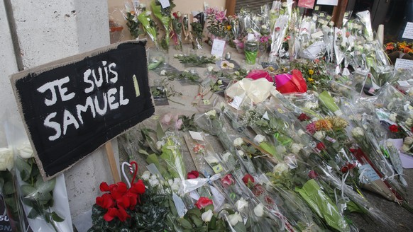 A poster reading &quot;I am Samuel&quot; and flowers lay outside the school where slain history teacher Samuel Paty was working, Saturday, Oct. 17, 2020 in Conflans-Sainte-Honorine, northwest of Paris ...