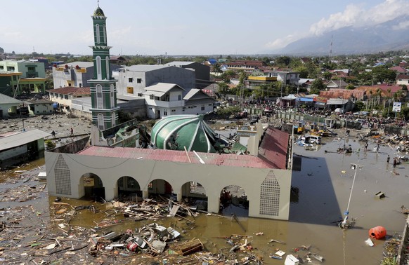 People survey the mosque damaged following earthquakes and tsunami in Palu, Central Sulawesi, Indonesia, Sunday, Sept. 30, 2018. A tsunami swept away buildings and killed hundreds on the Indonesian is ...