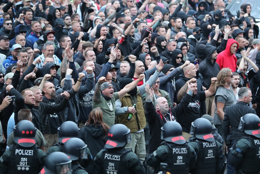 27.08.2018, Sachsen, Chemnitz: Polizisten stehen in der Innenstadt am Karl-Marx-Monument bei einer Kundgebung der rechten Szene, um ein Aufeinanderprallen von rechten und linken Gruppen zu verhindern. ...