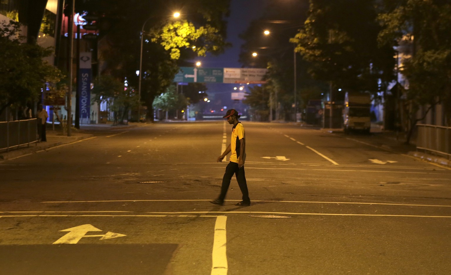 A Sri Lankan man walks across a deserted street during a curfew in Colombo, Sri Lanka, Sunday, April 21, 2019. More than two hundred people were killed and hundreds more injured in eight blasts that r ...