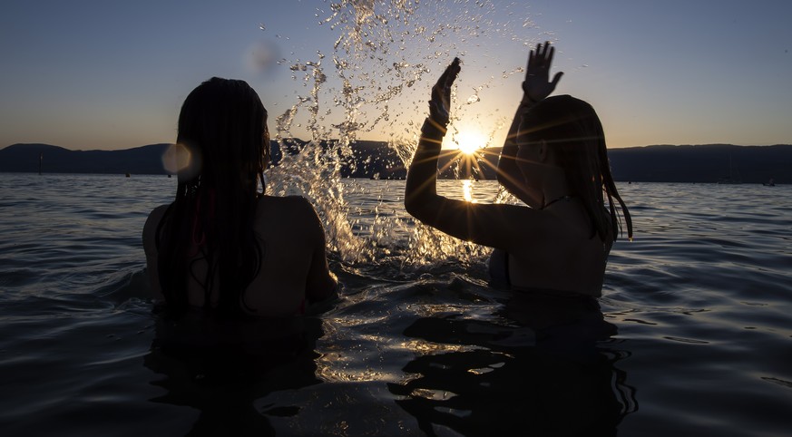 epa07681787 Two teenage girls enjoy the sunset in the water of the Lac de Neuchatel to cool off during the sunny and warm weather, in Gletterens, Switzerland, 28 June 2019, issued 29 June 2019. The fo ...